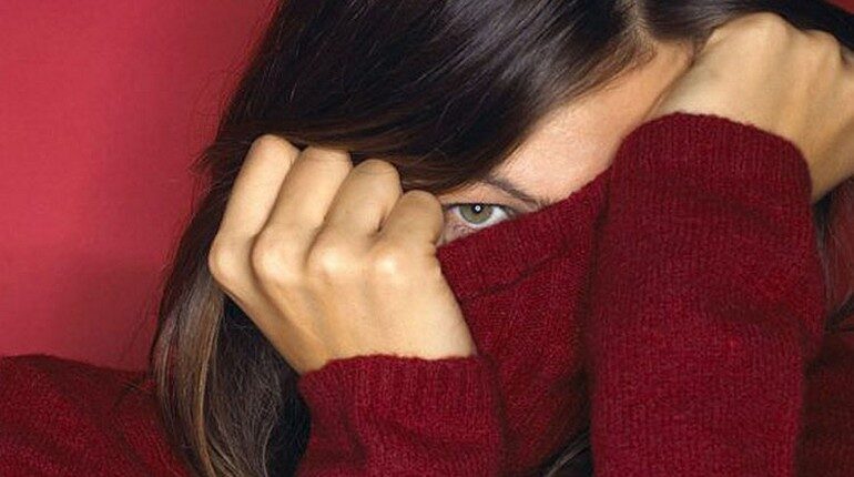 девушка закрыла лицо свитром, глаз девушки выглядывает из-под свитера