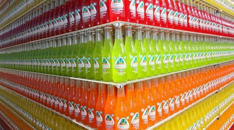 бутылки рассортированные на полках магазина, три полки с напитками разных цветов