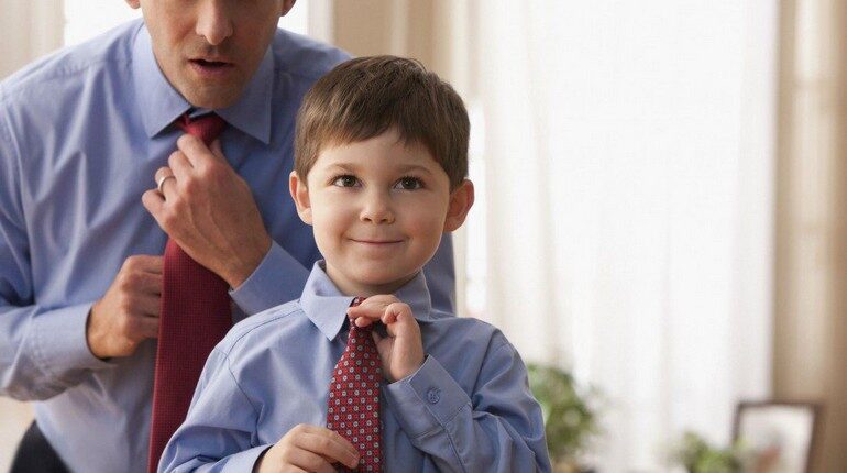 мальчик учится у папы завязывать галстук, маленький и большой в одинаковой одежде