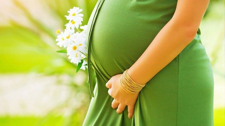 беременная в зеленом платье и ромашки