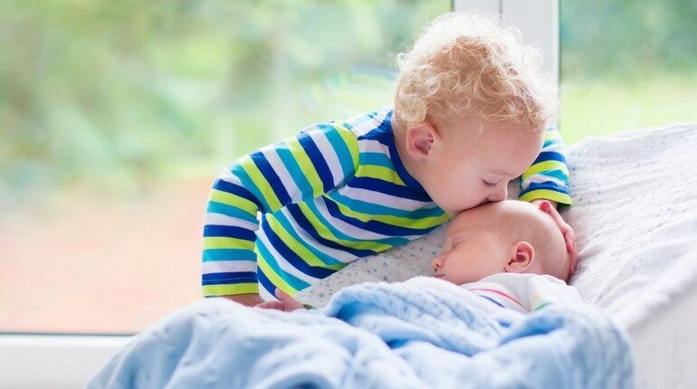 маленький ребенок целует новорожденного младенца