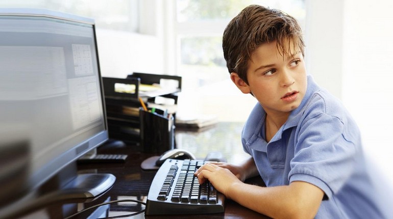 подросток сидит за компьютером, мальчик за клавиатурой