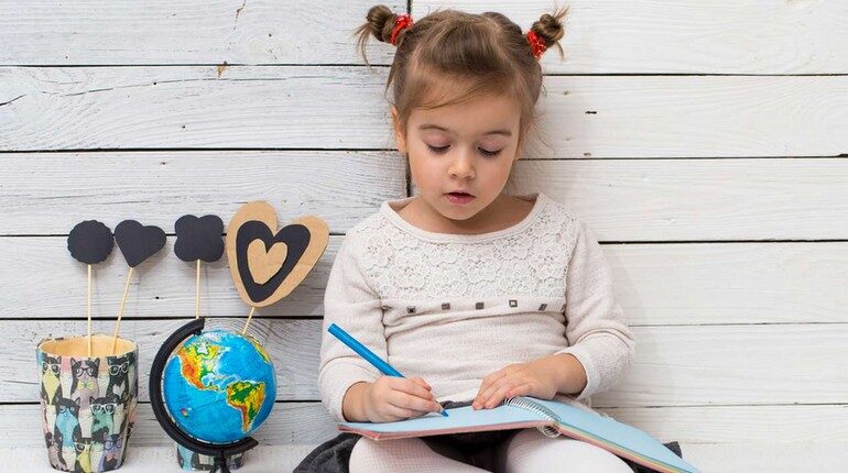 девочка что то пишет в блокноте, девчушка рисует, ребенок готов идти в школу