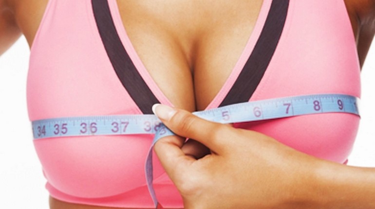 измерение объема груди, увеличение груди, девушка измеряет сантиметровой лентой свою грудь
