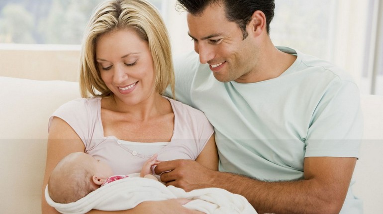 парочка с новорожденным ребенком, счастливые родители с новорожденным младенцем на руках