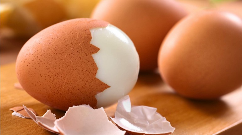 вареные яйца, одно яйцо наполовину очищено