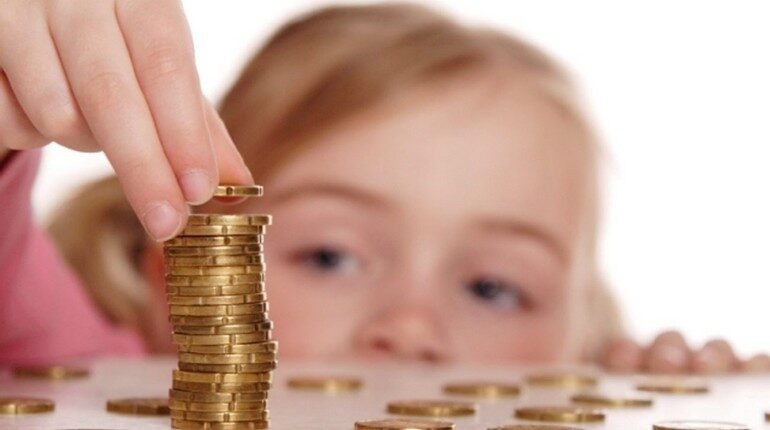 девочка смотрит на монетки, дети учатся обращаться с деньгами, воспитание ребенка