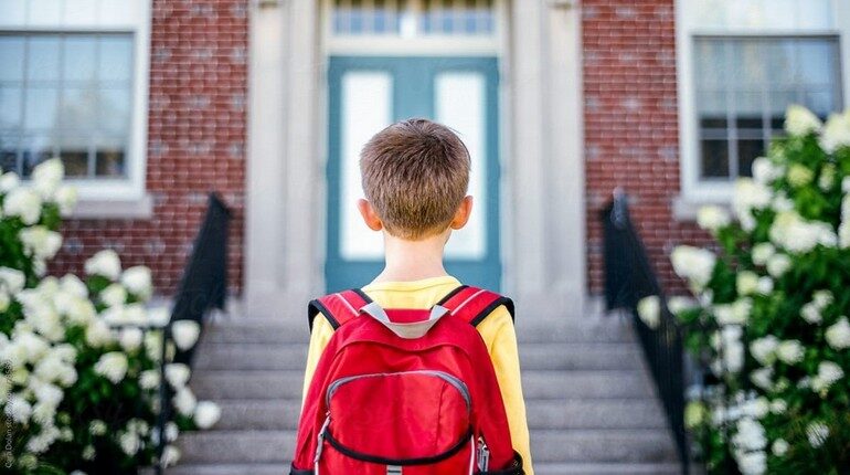 ребенок стоит лицом к школе, мальчик со школьным рюкзаком, парень идет в школу