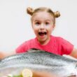 девочка и рыба на столе, ребенок радуется и держит огромную рыбину