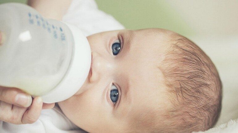 младенец кушает из бутылочки, кормление ребенка из бутылки