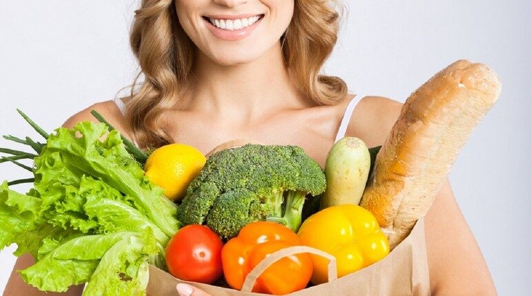 девушка держит в руке пакет с овоща и хлебом