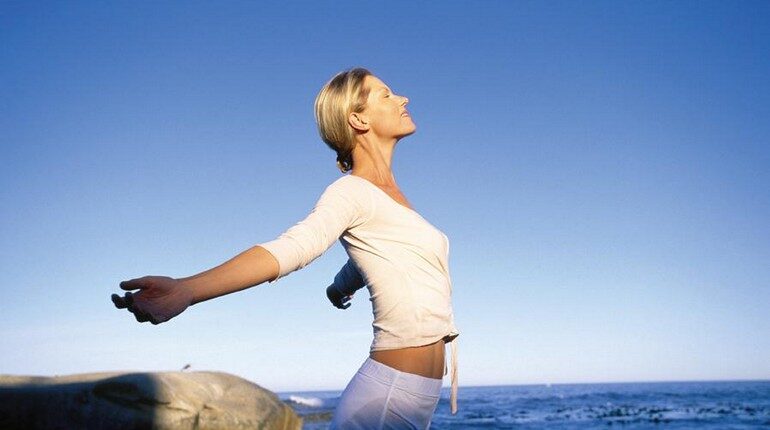 дыхательные упражнения на берегу моря, девушка занимается утренней гимнастикой на пляже