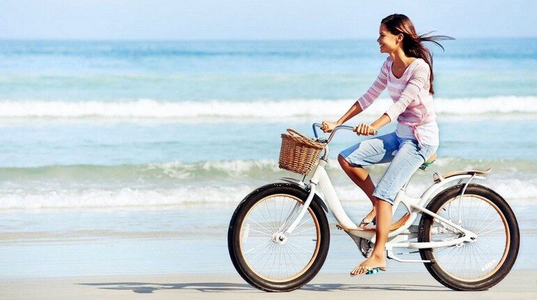 девушка едет на велосипеде, велопрогулка на берегу моря